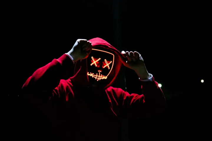 Man wearing red hoodie with neon LED mask
