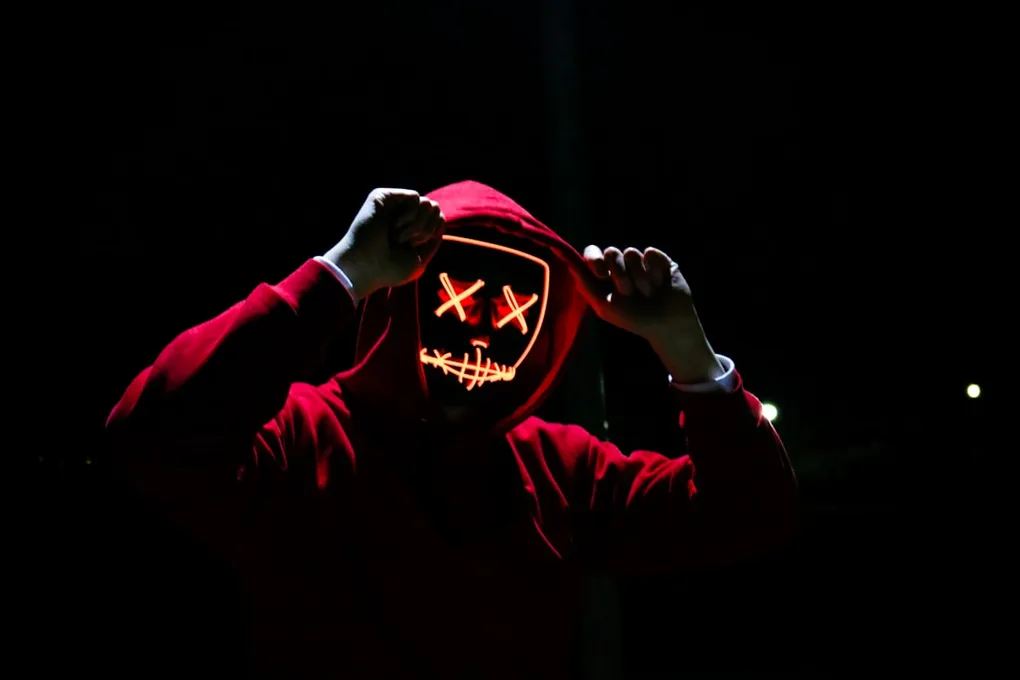 Man wearing red hoodie with neon LED mask